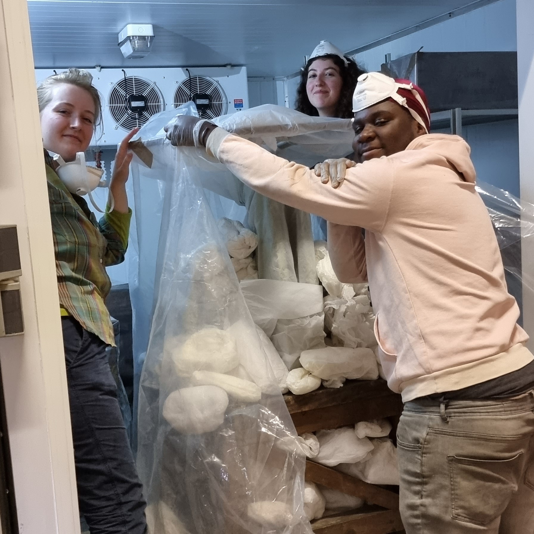Ricardo, Gabby and Sophie inside a freezer with an object wrapped in film and paper stuffing